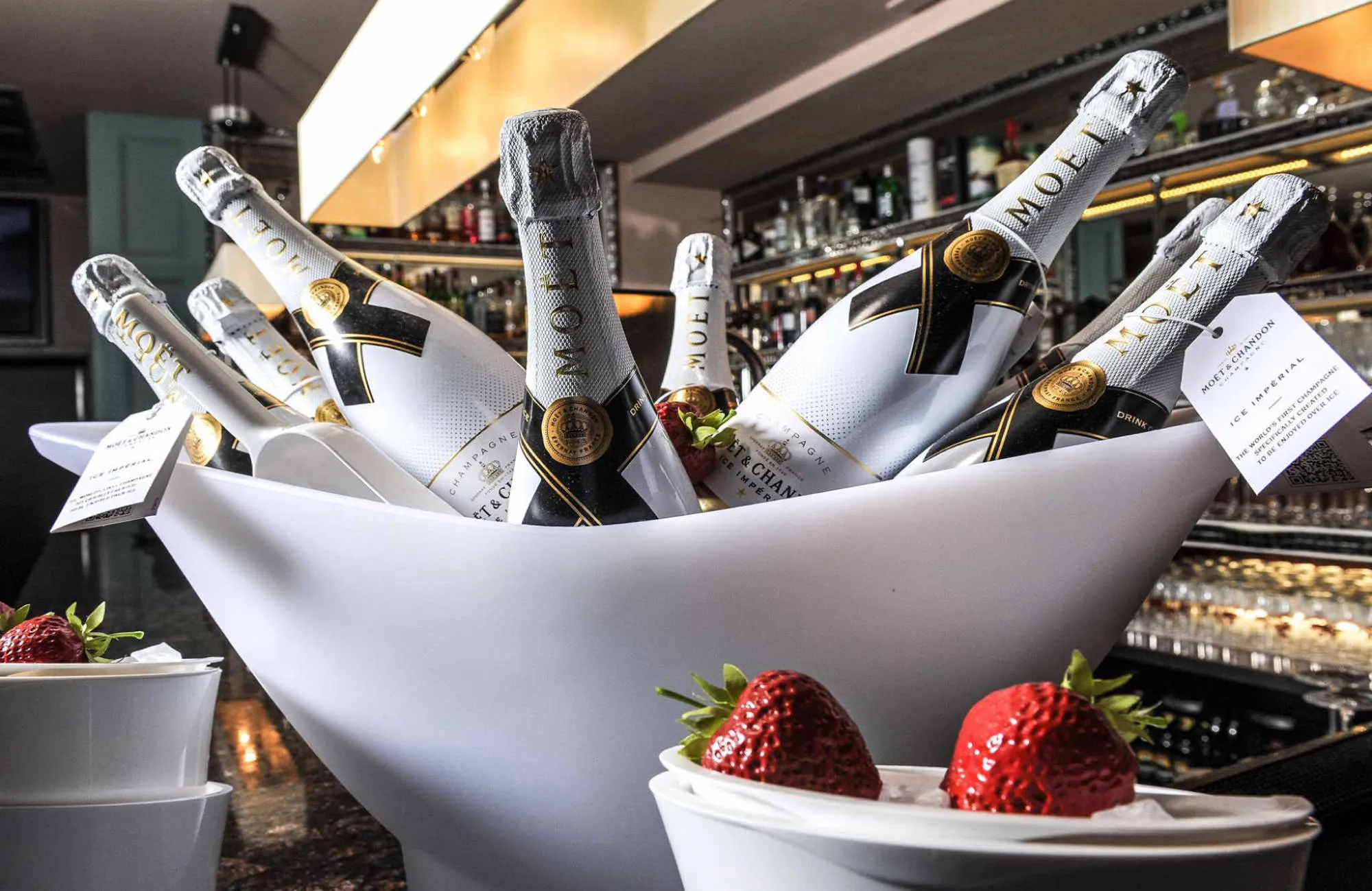 Bottles of champagne on ice with fresh strawberries