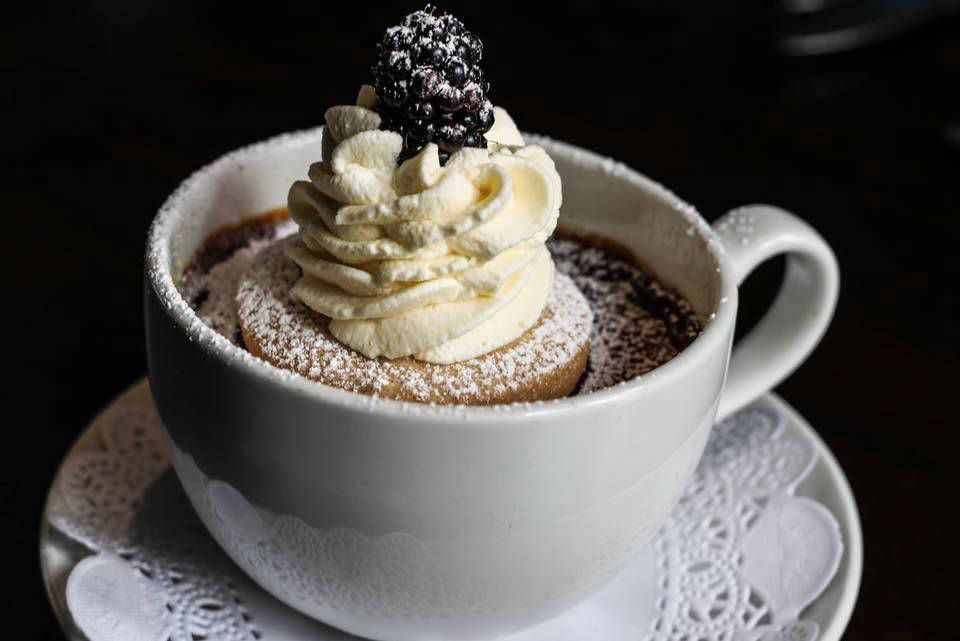 Chocolate dessert served in a cup with whipped cream and blackberry