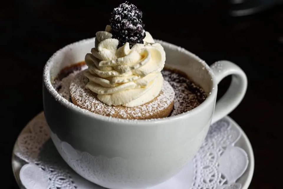 Chocolate dessert served in a cup with whipped cream and blackberry